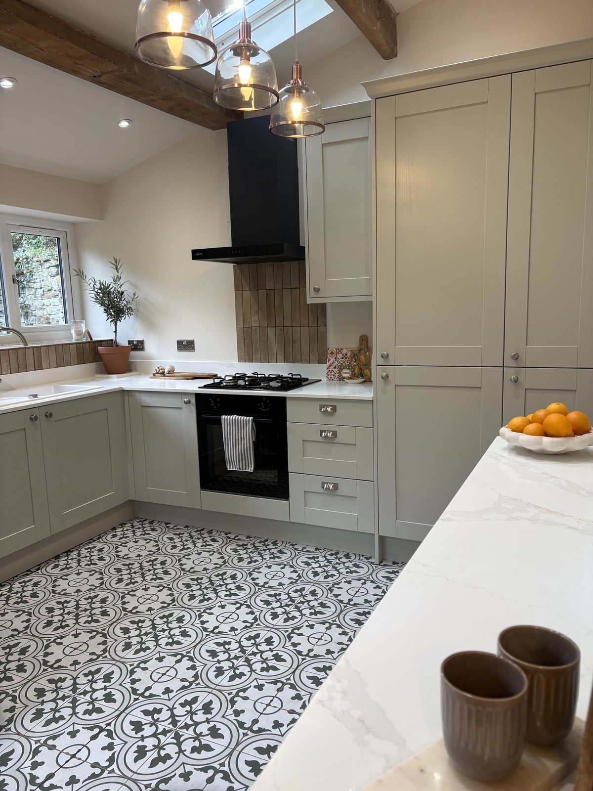New kitchen worktop and patterned floor tiles, with pendant lights above