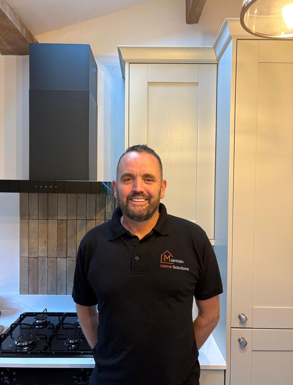 Lee, owner of Maintain Home Solutions, in his company polo shirt in a fitted kitchen